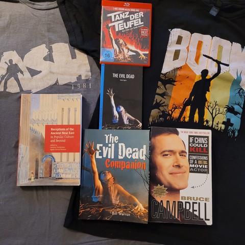 Das Bild zeigt meine Tanz der Teufel-Sammlung. 2 T-Shirts, den ersten Film sowie diverse Literatur zum Film.