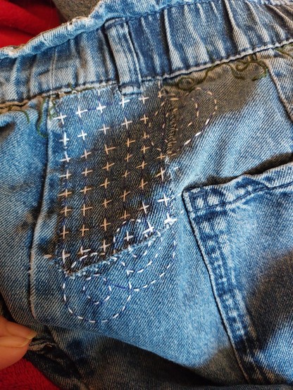 Mit Kreuzen und Kreisformen fixierter Jeansflicken