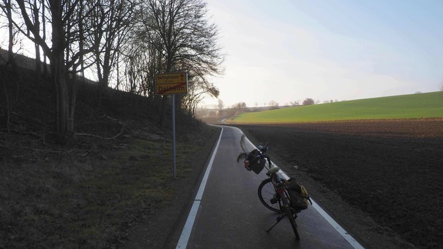 Radweg mit Fahrrad neben einem gelben Ortsausgangsschild.