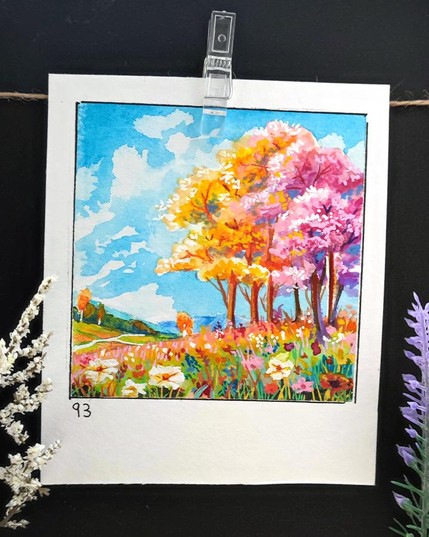 square watercolor framed with a black line on a rectangular, portrait-oriented paper. A vibrant meadow bursts into color, filled with wildflowers in shades of white, pink, and orange. A group of trees with golden-yellow and pink blossoms stands tall against a brilliant blue sky dotted with fluffy white clouds. Rolling hills stretch into the distance, adding depth to the dreamy landscape. The warm sunlight enhances the joyful atmosphere of this serene scene. Number 93 is written in the bottom left corner.