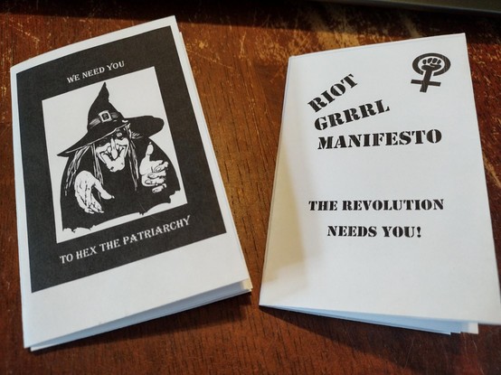 Minizine on left has an old witch pointing at you. Text: we need you to hex the patriarchy. Zine on right has Venus fist protest symbol. Text: riot Grrrl manifesto. The revolution needs you!