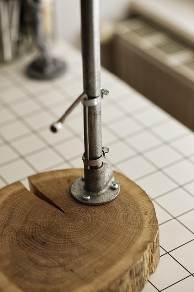 Detail photograph of a DIY clay stand, made of a wooden base and metal pipes.