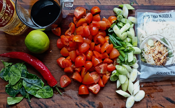 Die Zutaten vor dem Kochen auf einem Brett, Zwiebeln + Tomaten sind schon geschnitten.