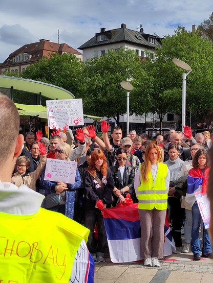foule silencieuse avec des pancartes, certains portent un gant rouge.