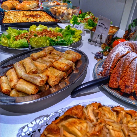 Ein Buffet-Tisch mit vielen leckeren Sachen: Kuchen, Frühlingsrollen, Salat und noch einiges gilt es zu entdecken. Guten Appetit.