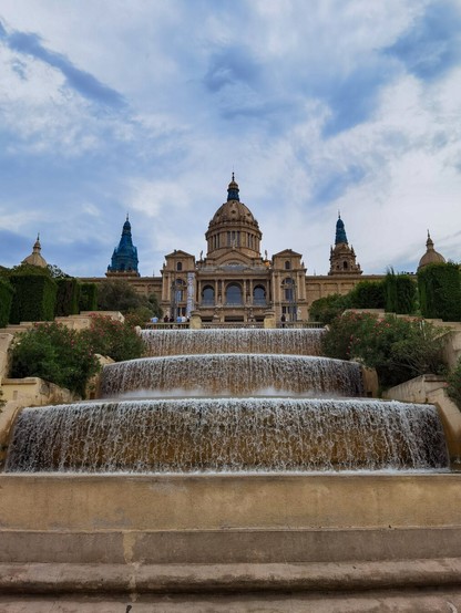 A grand historic building with cascading fountains in the foreground.