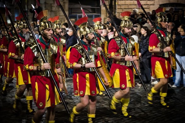 Roman soldiers marching on a street.