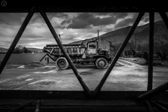 Monochrome shot of old dump truck shot through crane jib to frame