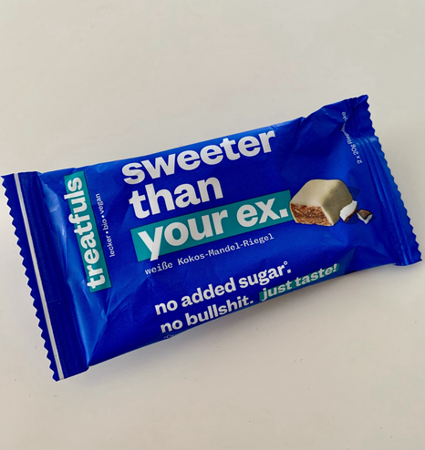 healthy coconut-almond bar from treatfuls. Wrapping is blue with teal-colored accents. White print on the wrapping reads: Sweeter than your ex. No added sugar, no bullshit. Just taste.
