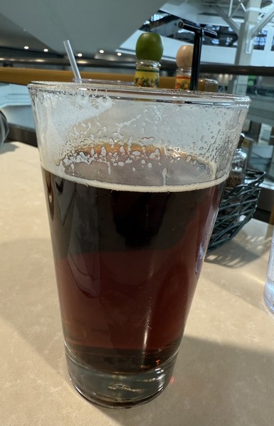 A pint glass full of light brown ale