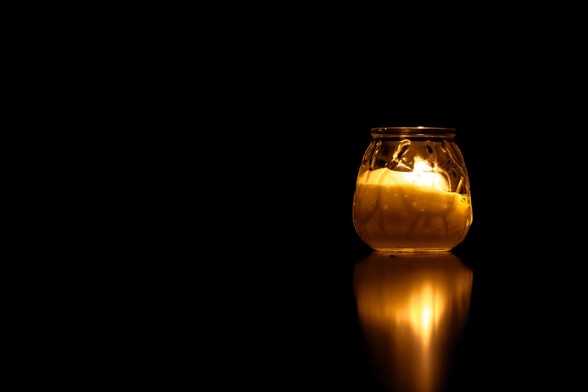 Photograph of a candle and its reflection surrounded by total darkness.