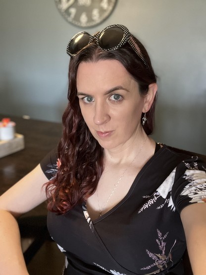 Selfie of the OP in a black floral v-neck top and oversized sunglasses.