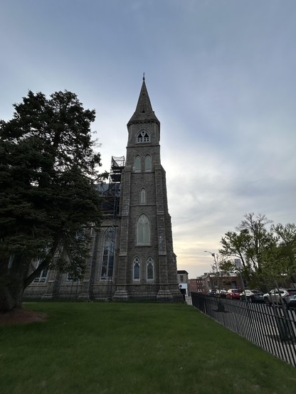 Exterior of a Gothic Revival Church at sunset. The view of of the steeple and side of the main building.