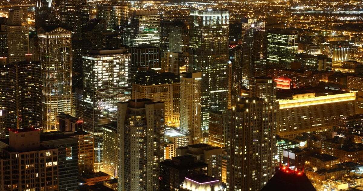 Das Bild zeigt die Innenstadt von Chicago mit zahlreichen Wolkenkratzern und greller Beleuchtung bei Nacht.