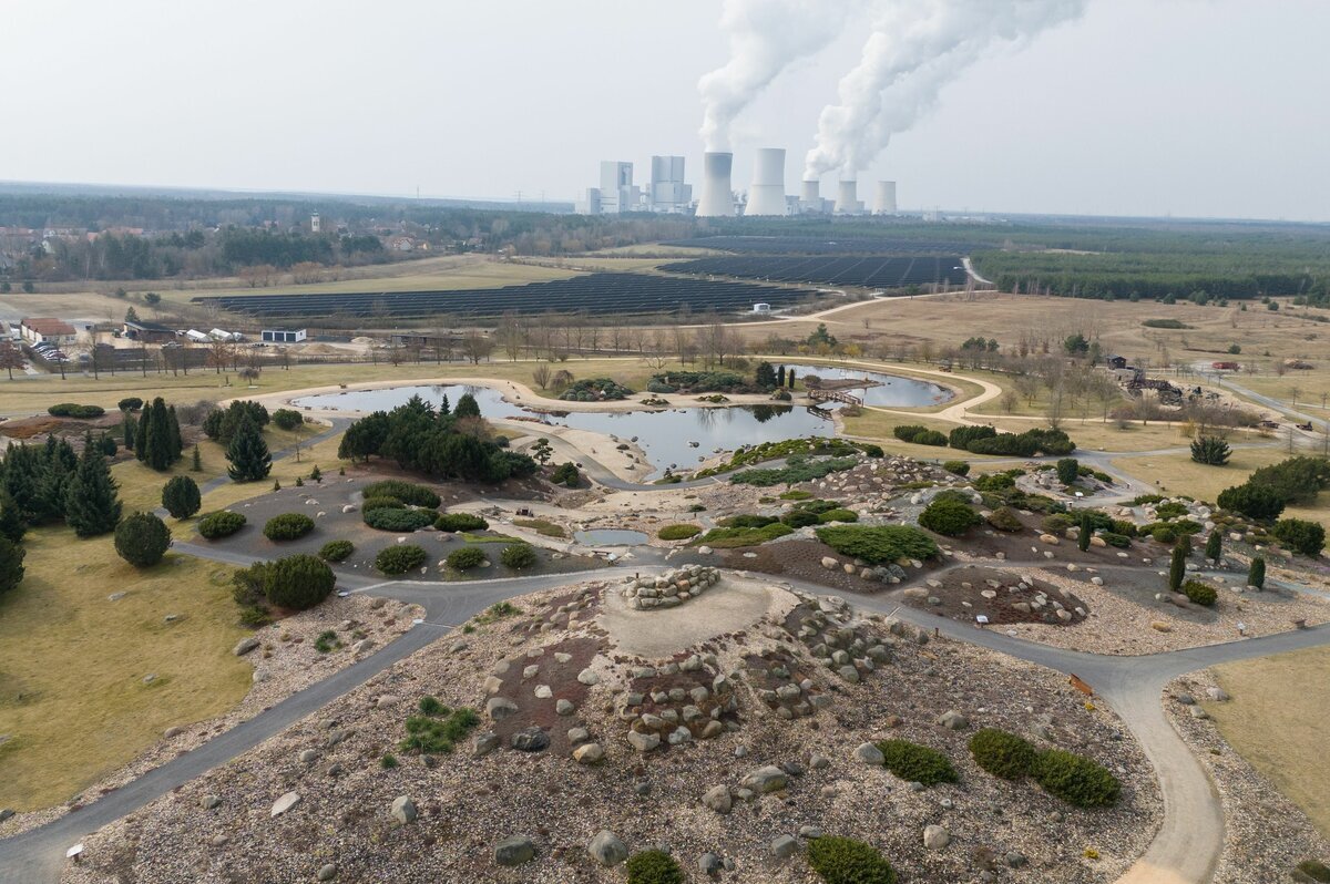 Eine Luftaufnahme zeigt einen renaturierten Bereich des Tagebaus Nochten vor der Kulisse des Braunkohlenkraftwerks Boxberg