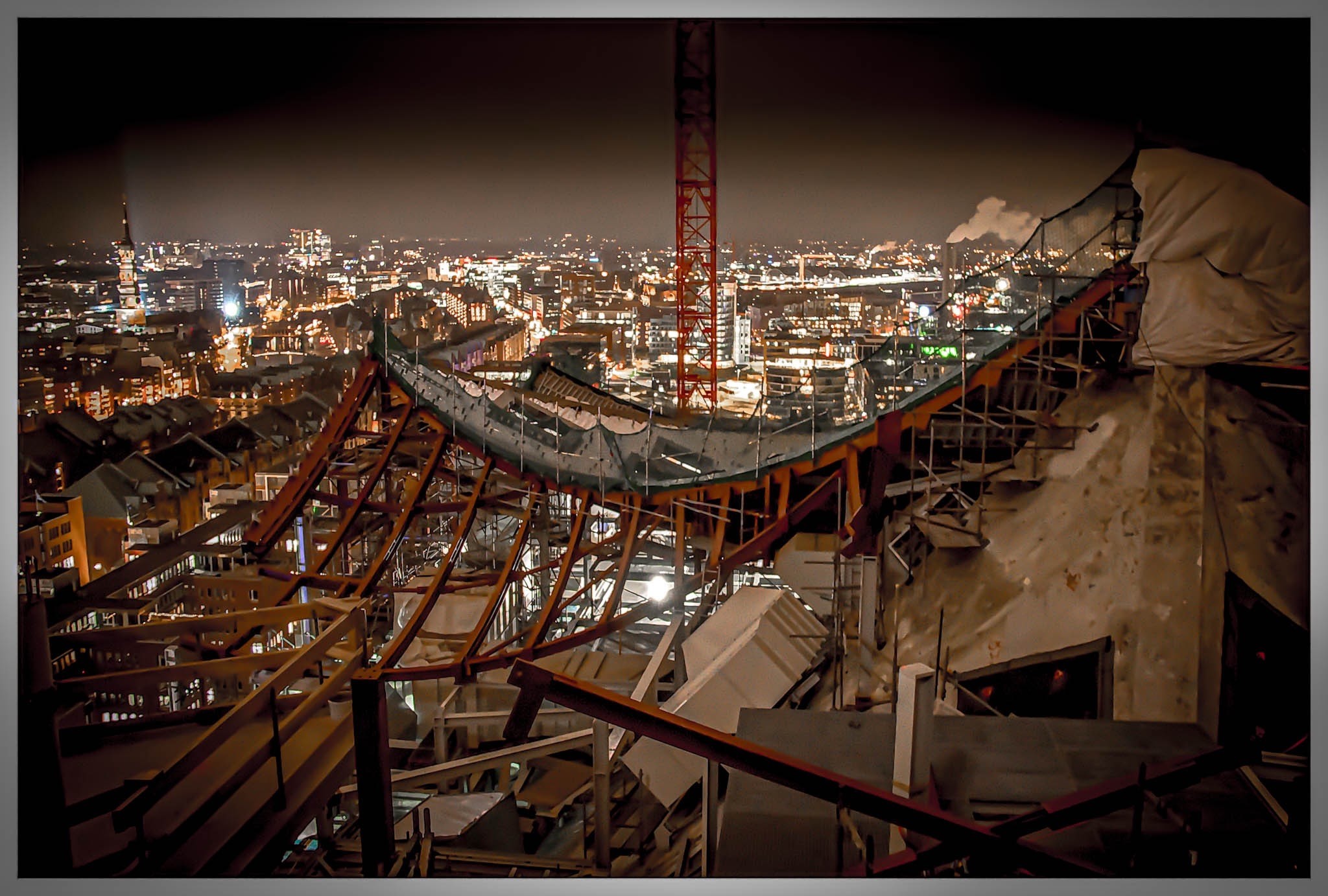 Eine nächtliche Stadtlandschaft, die ein teilweise errichtetes Gebäude mit freiliegenden Strukturelementen und Gerüsten zeigt. Die Skyline zeigt beleuchtete Gebäude im Hintergrund, die eine lebendige städtische Atmosphäre schaffen. Eine nächtliche Stadtlandschaft, die ein teilweise errichtetes Gebäude mit freiliegenden Strukturelementen und Gerüsten zeigt. Die Skyline zeigt beleuchtete Gebäude im Hintergrund, die eine lebendige städtische Atmosphäre schaffen.