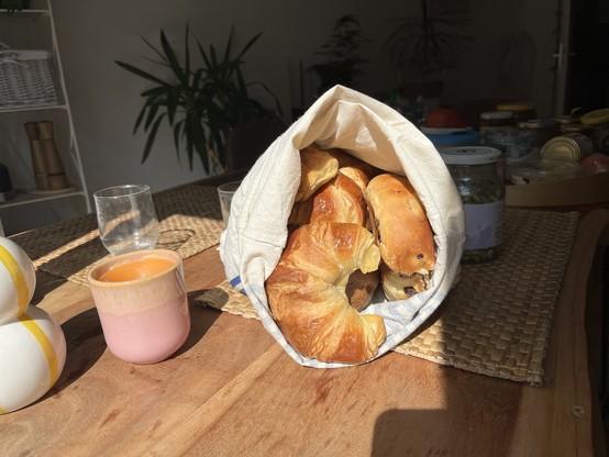 Eine Tüte frischer Brötchen, Croissants und Rosinenbrot