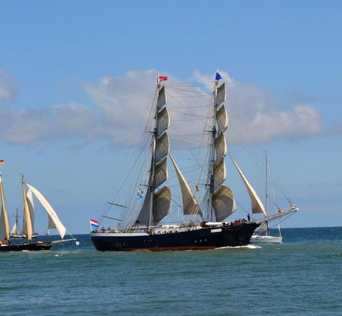 Zweimastiges Segelschiff mit schwarzem Rumpf unter vollen Segeln.