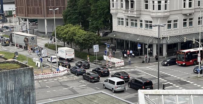 Blick auf eine Kieler Kreuzung. Auf einem Teil der Straße ist eine Baustelle zu sehen. Der Autoverkehr ist dadurch eingeschränkt. Ein Stau zieht sich komplett von der einen zur anderen Seite der Kreuzung. Bremslichter verraten den Stillstand. Der von rechts querende Verkehr steht noch ordentlich an der Haltelinie wartend. Darin ist auch ein Bus zu sehen.