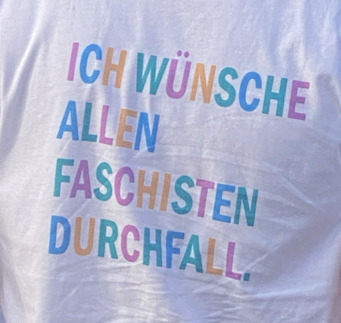 Aufdruck eines Shirts: Ich wünsche allen Faschisten Durchfall. Jeder Buchstabe hat eine andere Farbe als die Buchstaben daneben.