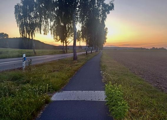 Radweg im Sonnenuntergang mit gepflasterter Reparaturstelle.