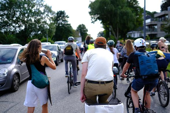 Nelly Waldeck auf Skates und Maik Kristen auf einem Fahrrad bei der FFF Exit Gas Enter Future Demo. Auf dem Fahrradkorb hängt ein Hoody mit der Aufschrift "Scheisse Autobahn #nobau"