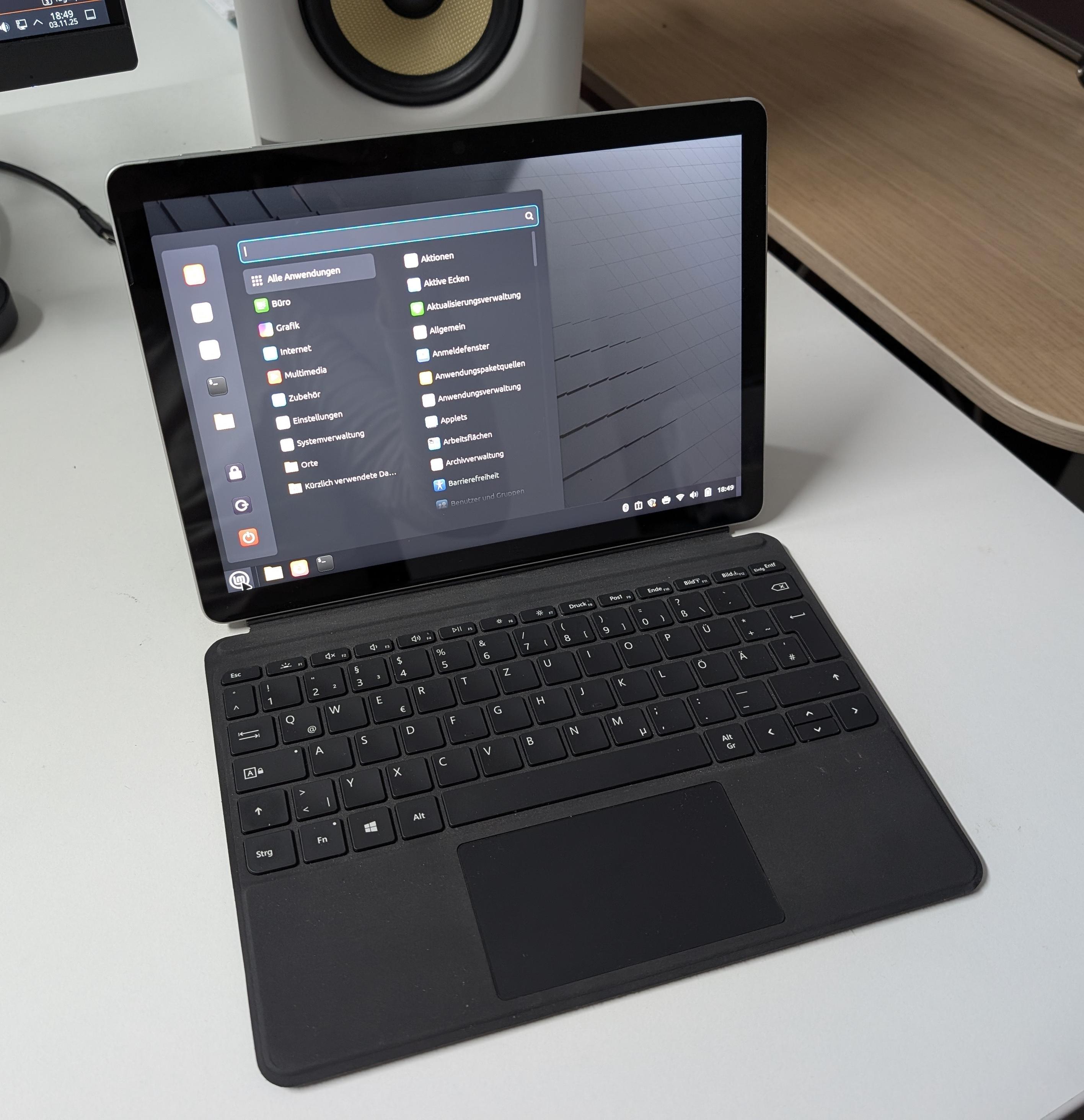 Ein kleines Surface Go 2 Notebook. Auf dem Bildschirm ist der Linux Mint Desktop mit geöffnetem Startmenü zu sehen.