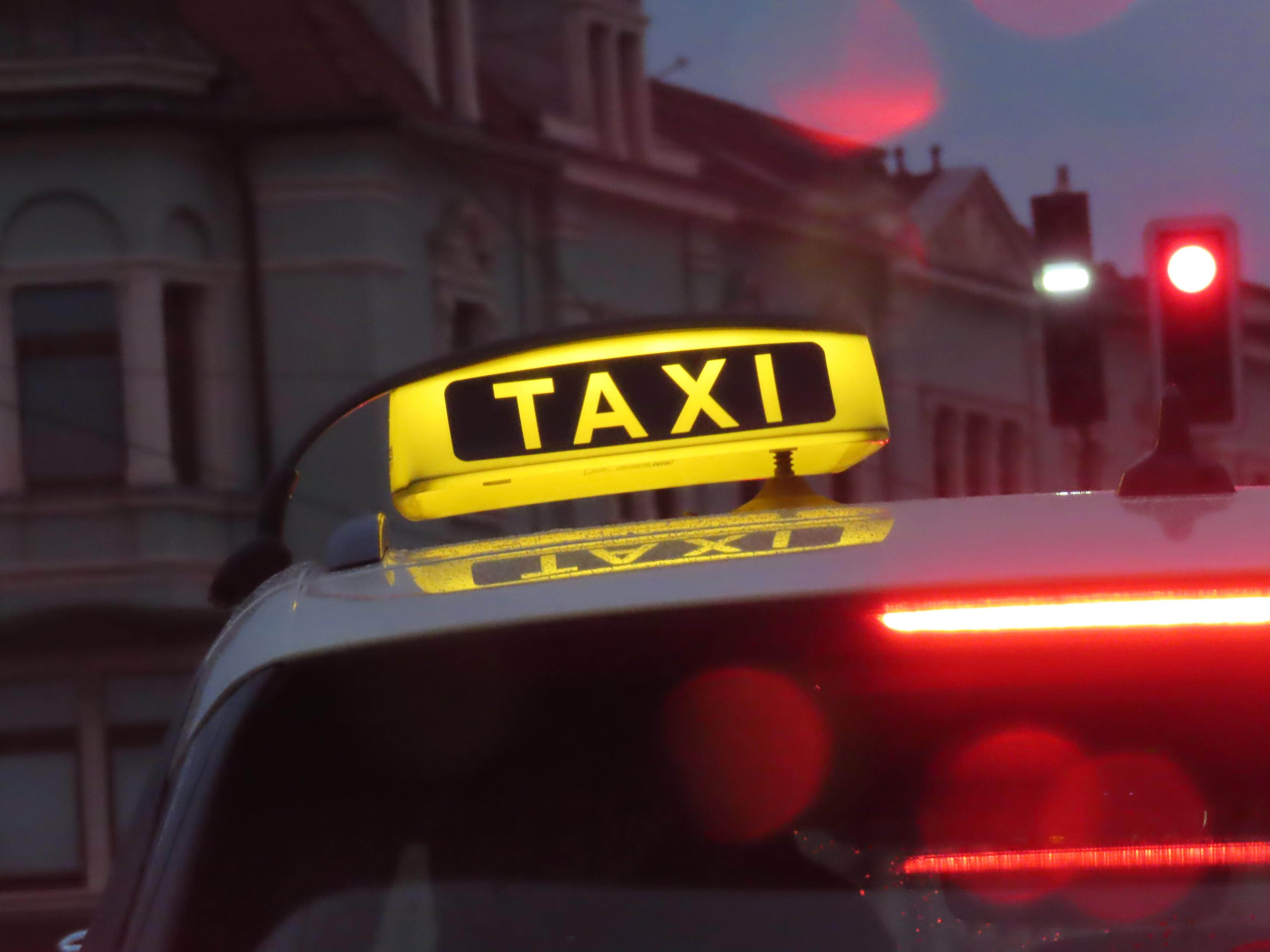 Taxischild, das leuchtet.
Das Taxi steht an einer roten Ampel