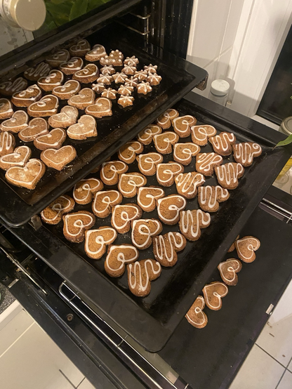 Drei Bleche mit Pefferkuchenherzen, verziert mit Zuckerguss.