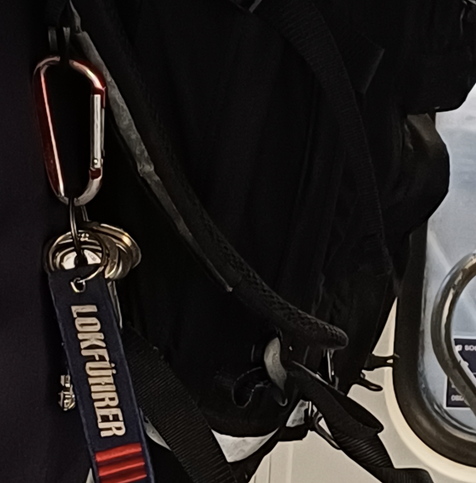 Rucksack mit Schlüsselanhänger auf dem Lokführer steht.
