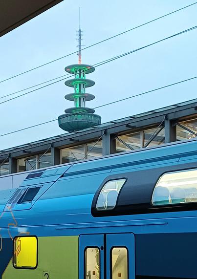 Funkmast als stilisierter Weihnachtsbaum. Im Vordergrund ein Zug.