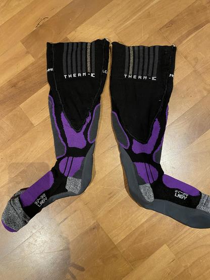 zwei lila-schwarze Strümpfe liegen platt auf Holzfußboden. Man sieht, wenn man genau hinsieht, die eingefügten Keile. Sie sind nicht ganz identisch.