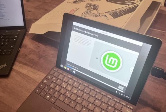 Surface mit dem Linux-Installationsbildschirm und KiPi-Pizzakarton im Hintergrund