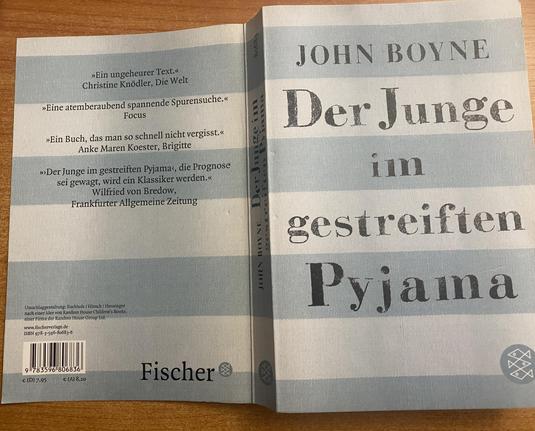Das Buch: Der Junge im gestreiften Pyjama von John Boyne liegt offen mit dem Rücken nach oben, so das man die Empfehlungen von WELT, FAZ Focus und Brigitte lesen kann.