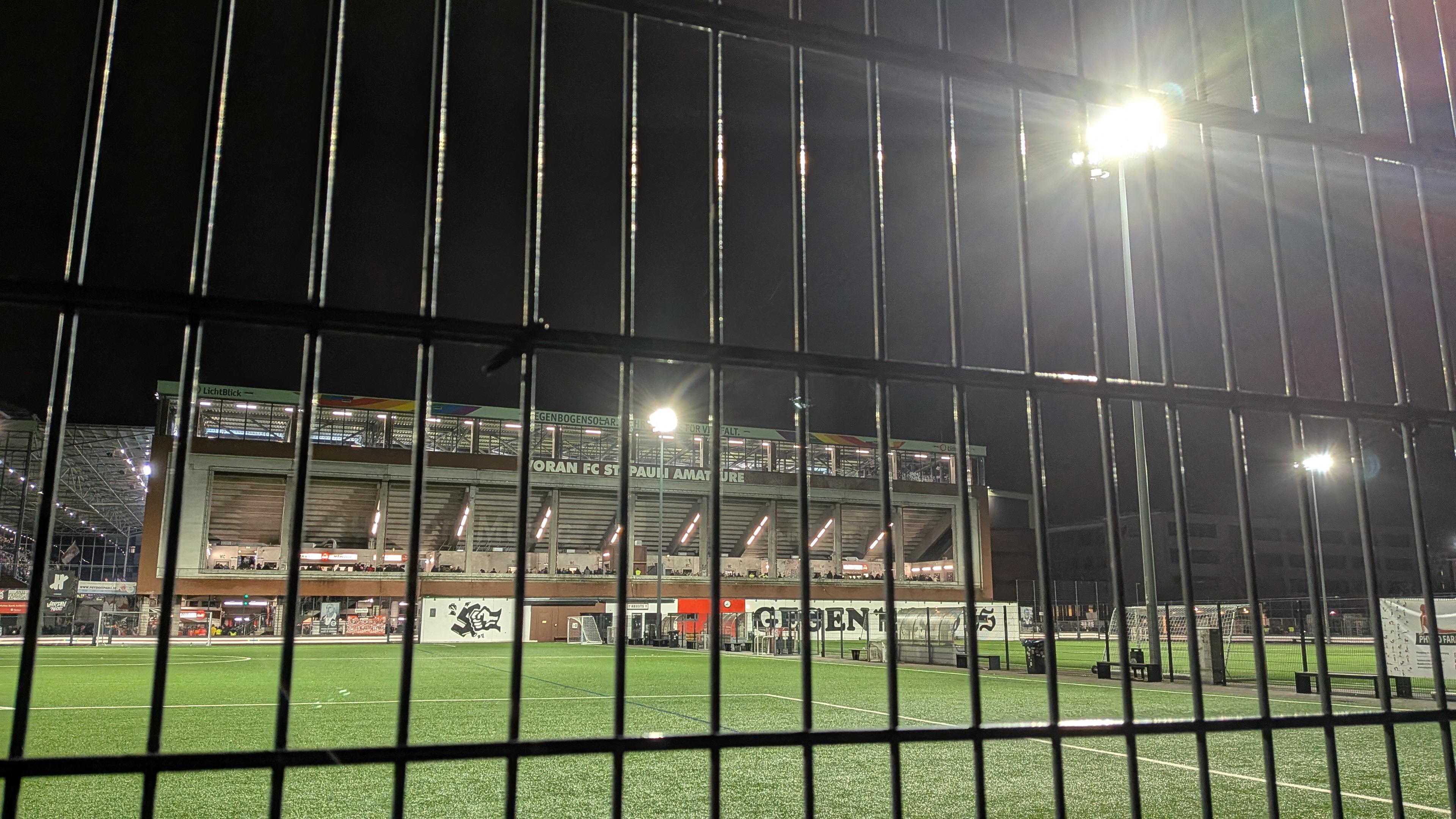 Stadion Nord Außenbereich. Davor ein Kunstrasenplatz und eine große Hand auf einer Rückwand, die ein Hakenkreuz zerschlägt.