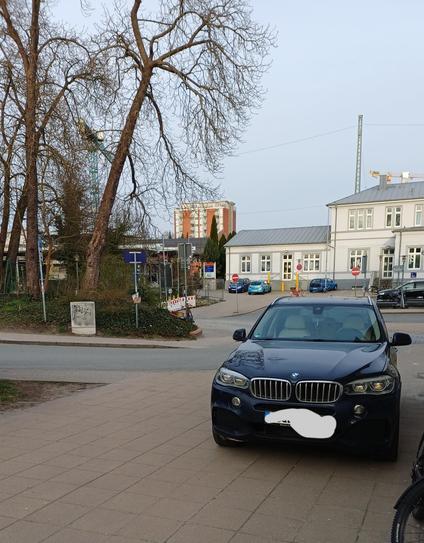Parkendes Auto auf Gehweg zwischen Bahnhofsteilen.