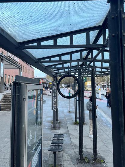 Ein Fahrrradrad hängt im Dach einer Bushaltestelle angeschlossen 