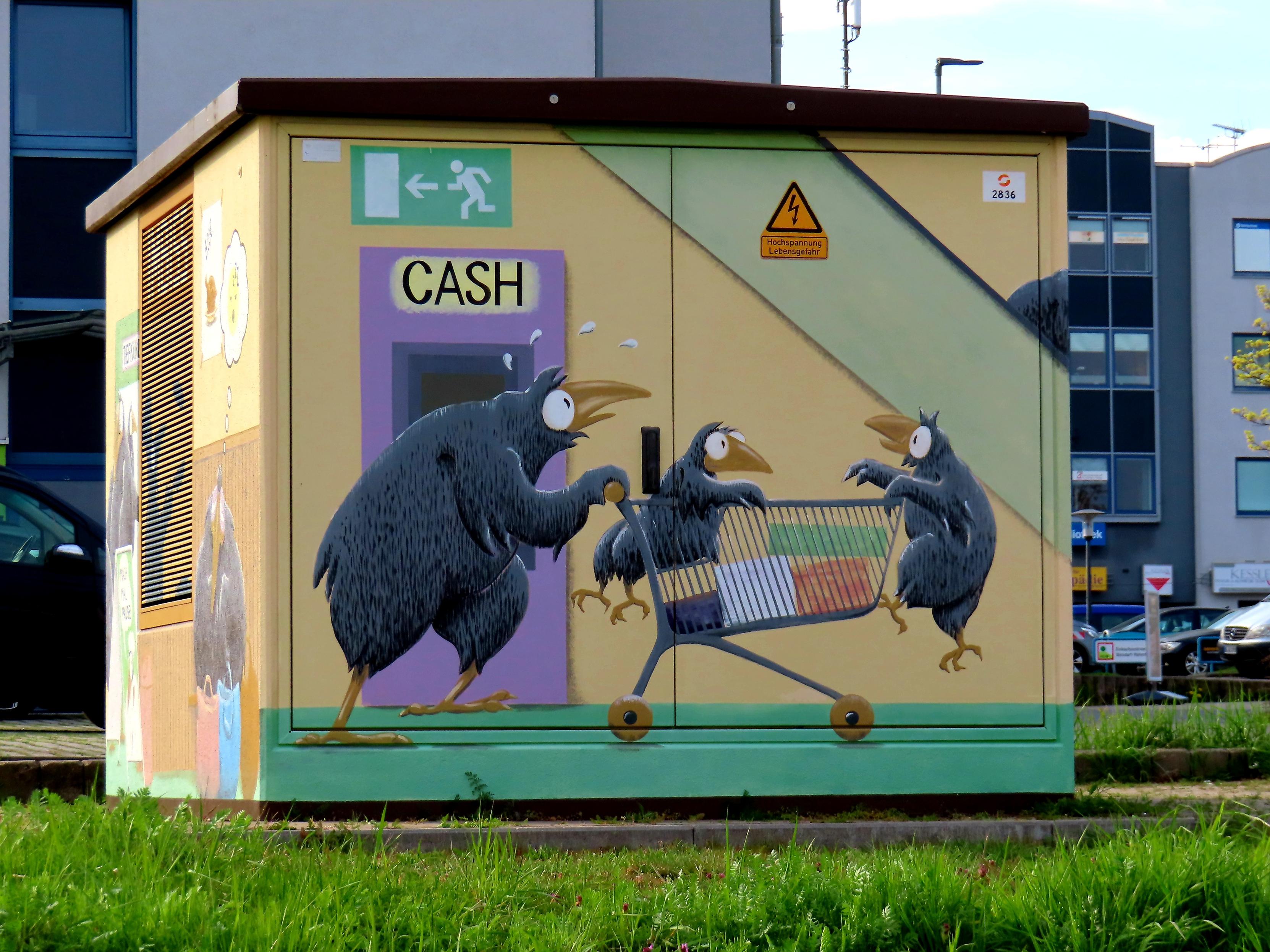 ElektroHäuschen 

Ein Rabe mit Einkaufswagen.
2 kleine Raben. Einer sitzt im Wagen, der andere klettert am vorderen Ende. Päckchen liegen im Wagen.

Eine Szene aus einem Einkaufsmarkt.
Ein Geldautomat (Cash) in lila, das grünWeiße Schild für NotausgangsHinweis, alles sichtbar