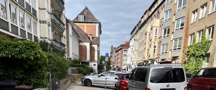 Ein Auto steht quer über den Fußweg geparkt im Weg