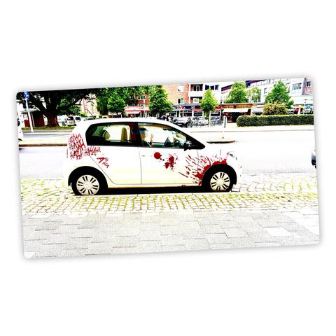 Ein Auto in einer Parklücke. An dessen vorderen Kotflügel und der Beifahrertür sind Blutspritzer großflächig dargestellt. Über dem hinteren Kotflügel und der C-Säule ist in gleicher blutroter Farbe wie mit Fingerfarben „HA HA HA HA HA HA…“ geschrieben.