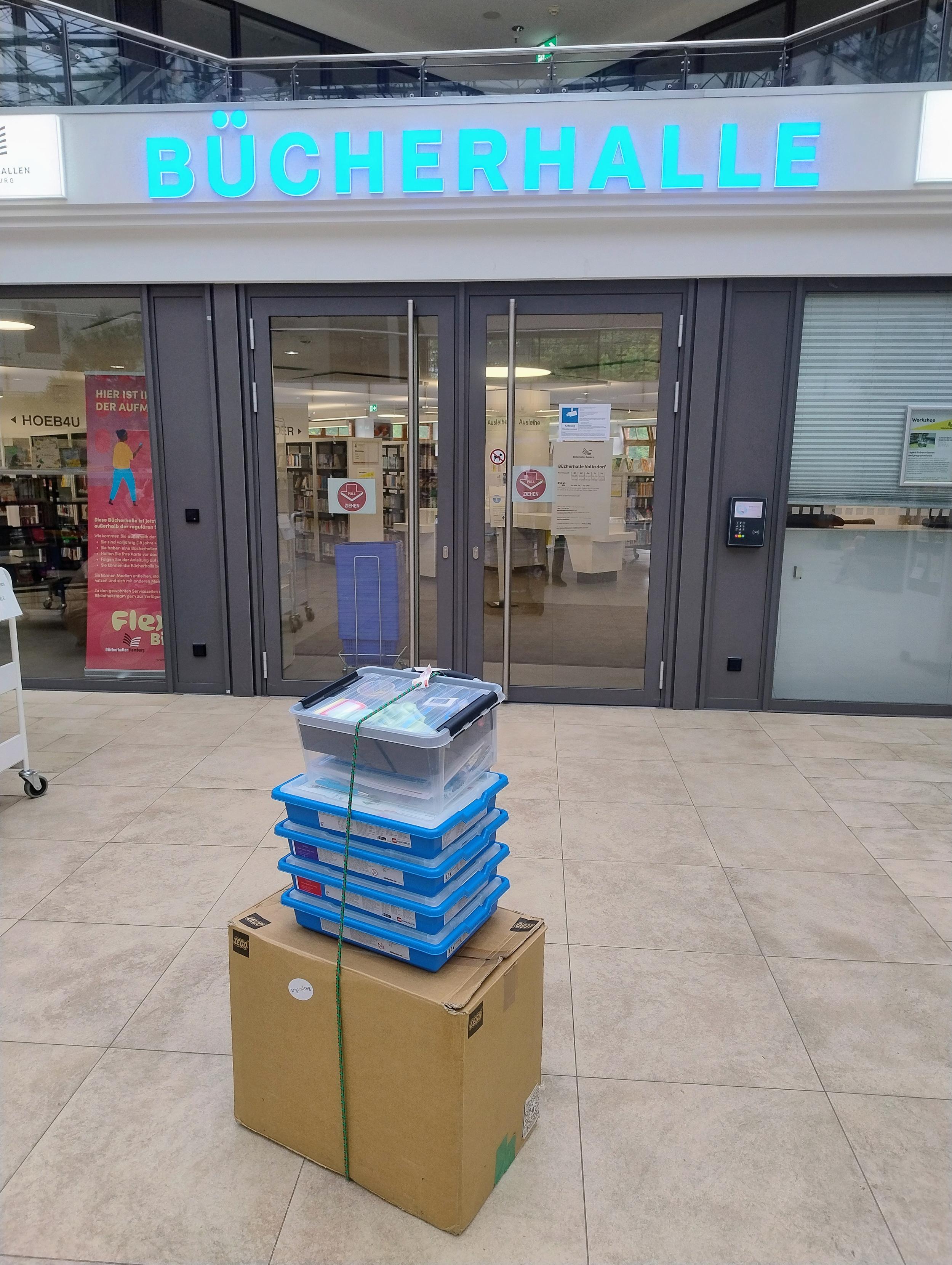 Vor dem Eingang zur Bücherhalle steht mein Wägelchen mit den Lego-Sets.