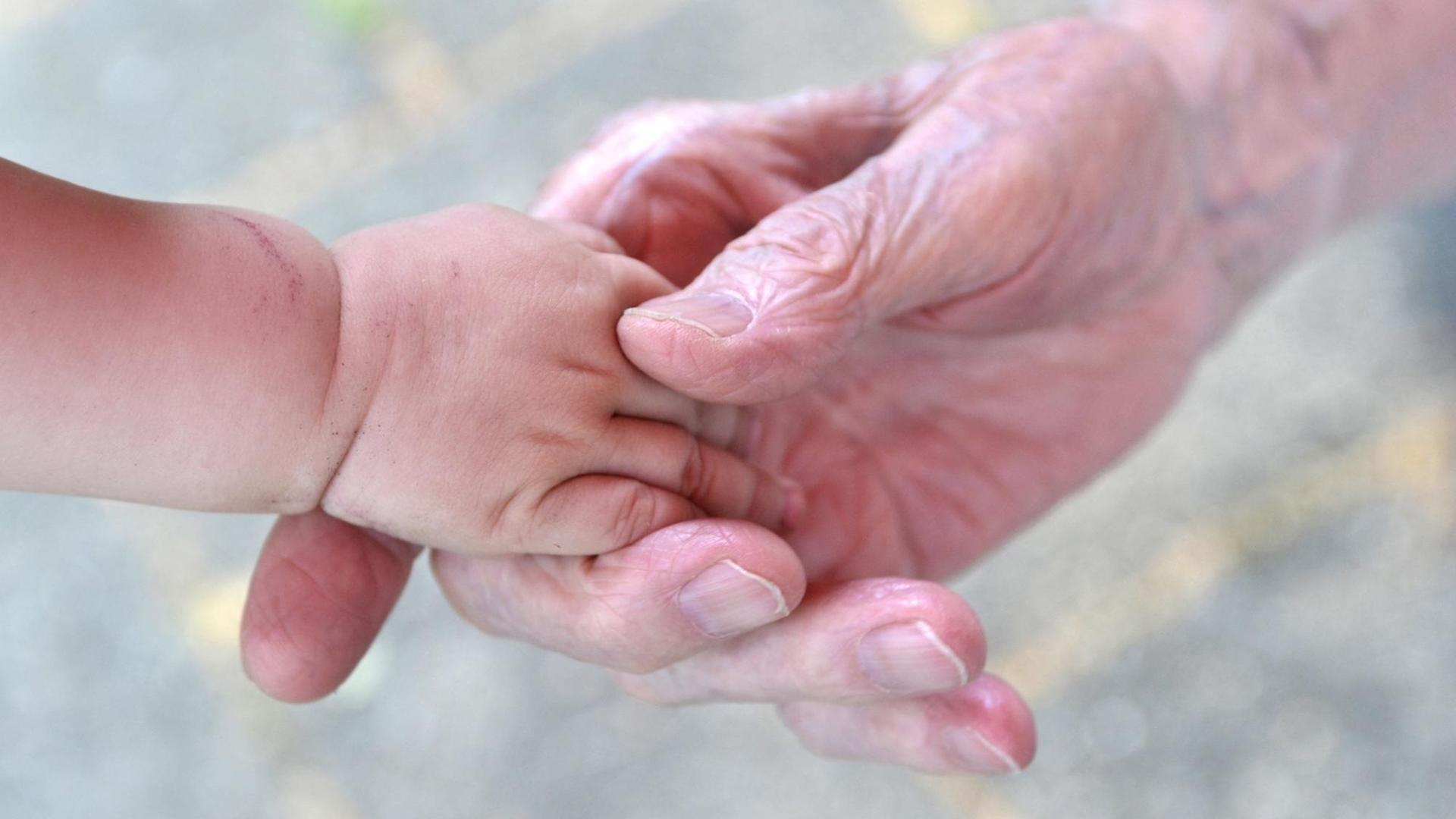 Alter Mensch gibt jungem Mensch die Hand.