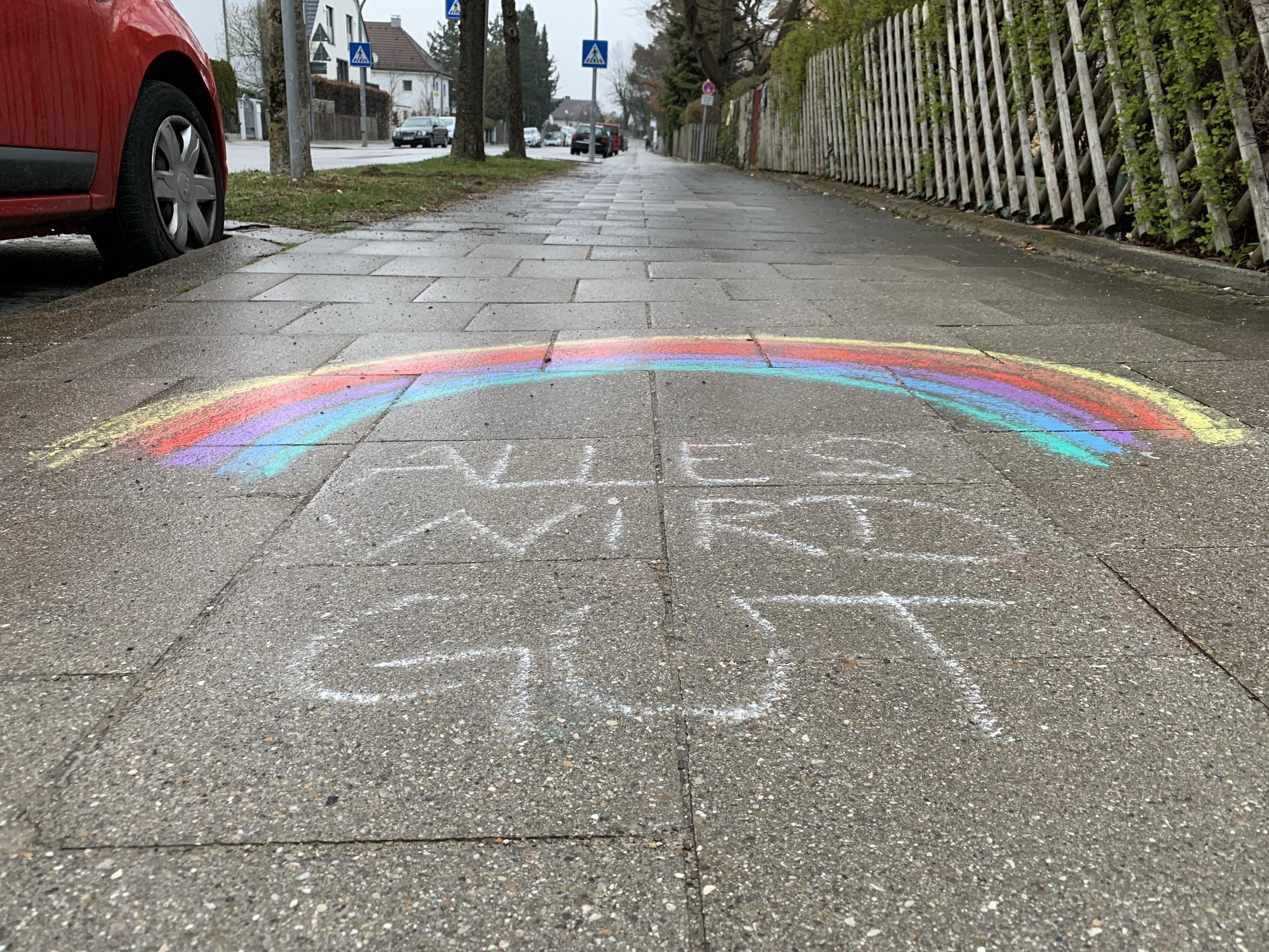 Kinder haben mit farbiger Kreide einen Regenbogen aufs Pflaster gemalt und „Alles wird gut“ darunter geschrieben. Aufgenommen 2020