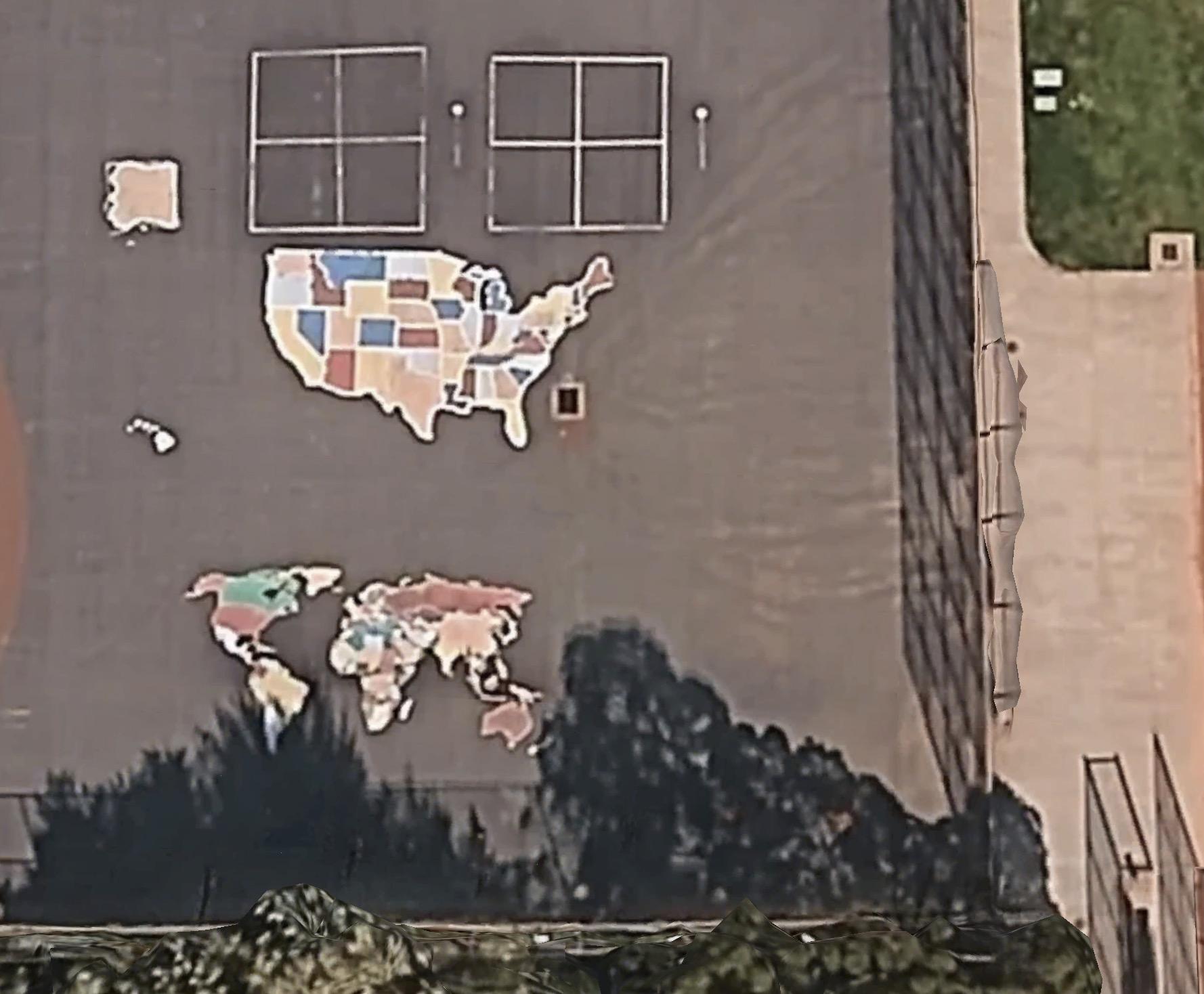 google Earth Luftbild eines Schulhofes. Auf dem Asphalt sieht man eine Landkarte der USA und eine Weltkarte. Die Staaten sind jeweils bunt eingefärbt.