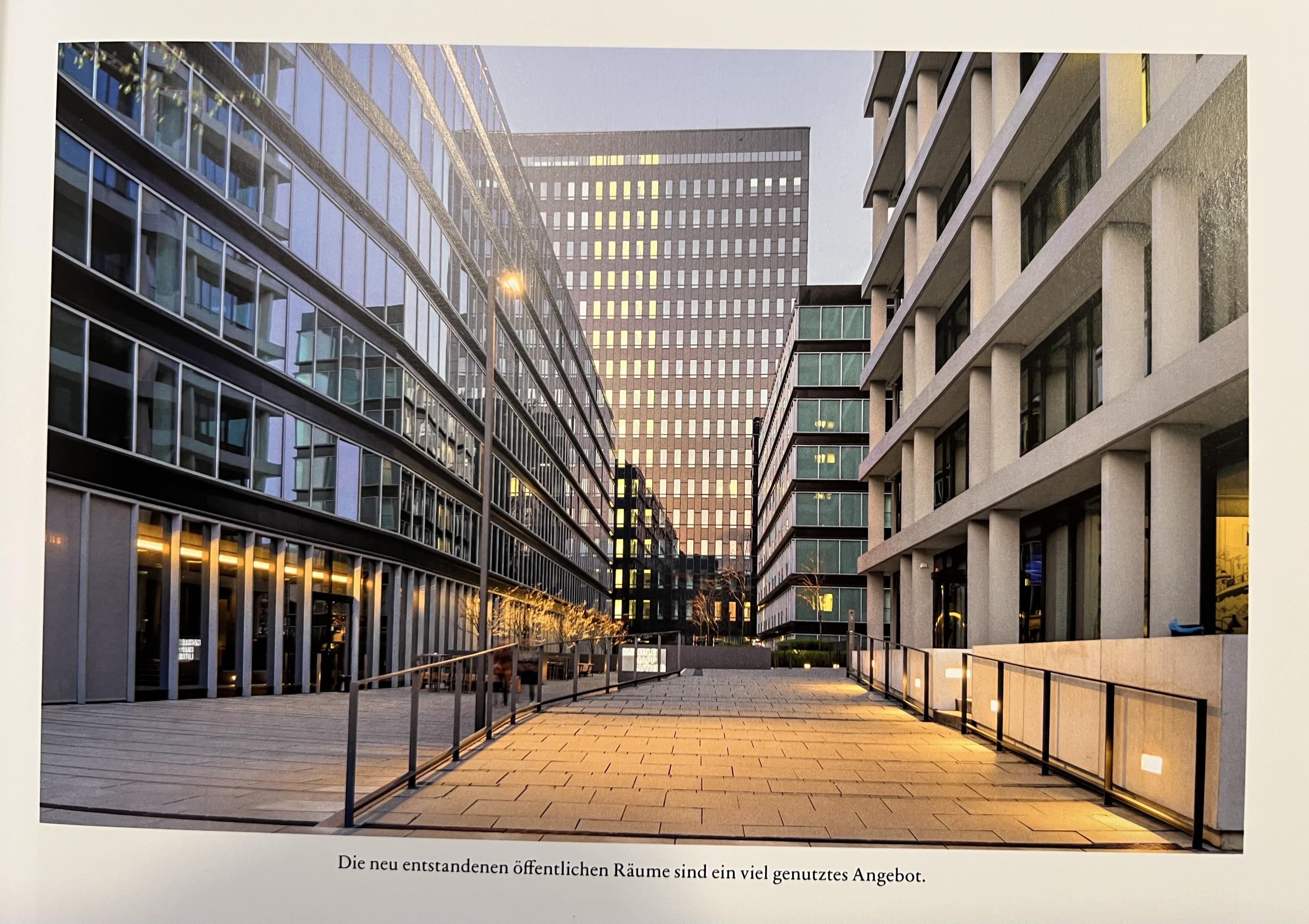Foto aus einem Architekturbuch: Hochhäuser um einen menschenleeren Platz. Bildunterschrift: Die neu geschaffenen öffentlichen Räume sind ein vielgenutztes Angebot.