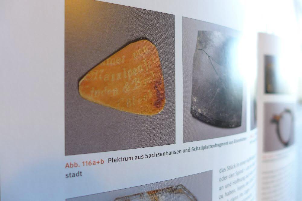Foto in ein Buch, auf der Seite auf der es aufgeschlagen ist, ist ein Plektrum abgebildet. Da steht "Marzipan" drauf.