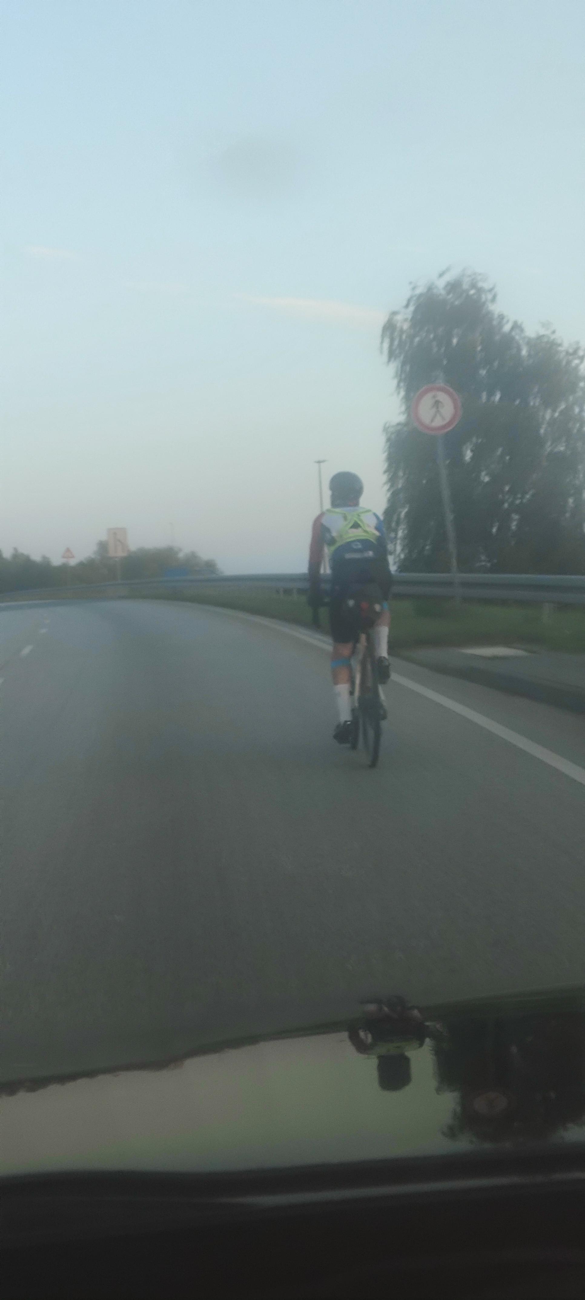 Ein Teilnehmer des TCRNo12 verlässt mit seinem Rad den Rostocker Hafen auf einer 2-spurigen Straße.
