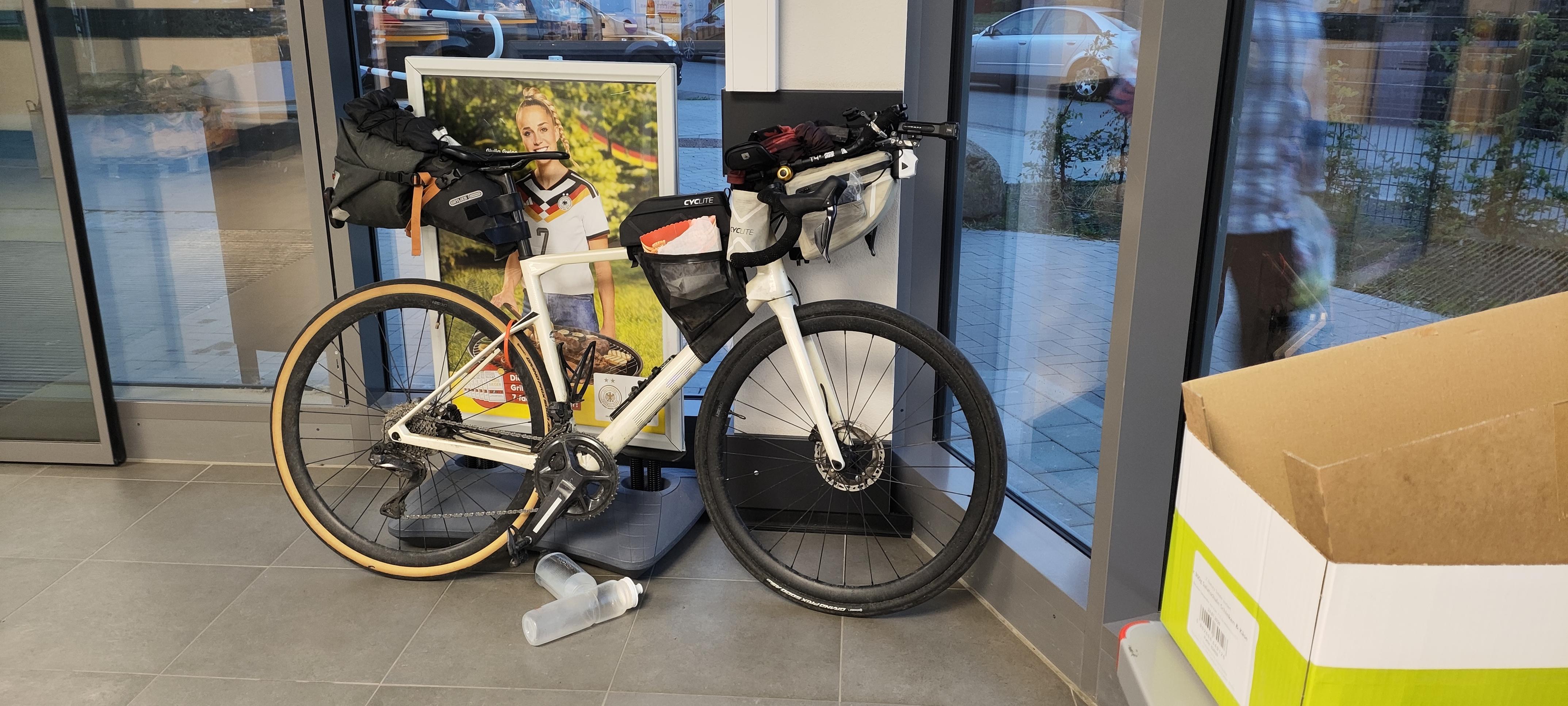 Ein Rennrad mit Gepäcktaschen steht im Foyer eines Supermarktes.