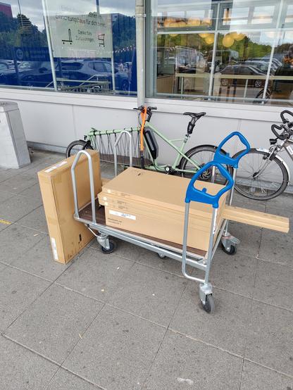 Ein voller IKEA Einkaufswagen vor einem leeren Lastenrad