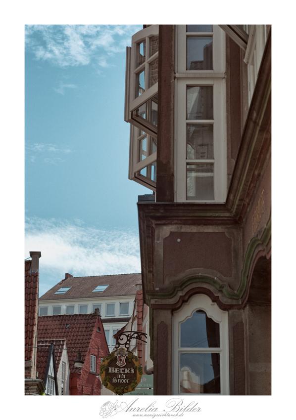 Ein Erker von einem sehr alten Haus ragt seitlich ins Bild. Die Sprossenfenster sind leicht geöffnet.